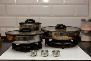 On the stove in the kitchen there are pots and pans under lids, cooking, for family, lunch, dinner