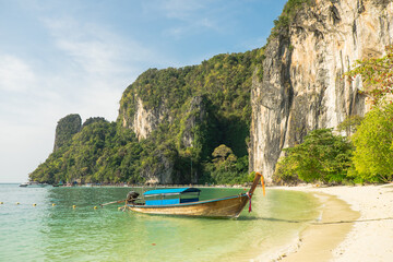 Beach and cliffs on a tropical island with boat docked near the shore