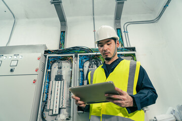 Professional Electrical Engineer or Electrician service working use tablet inspection electrical at control panel room. Maintenance Engineer check or repair electrical control panel.