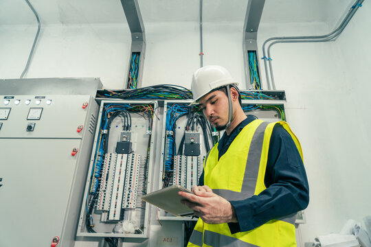 Maintenance Engineer check or repair electrical control panel. Professional Electrical Engineer or Electrician service working use tablet inspection electrical at control panel room.