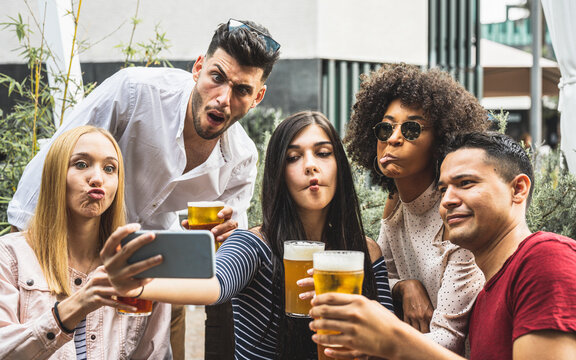 crazy selfie time of a millennials group of friends, people drinking beers and having fun using smartphone for making memories