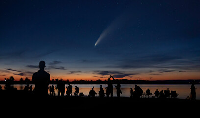 Comet Neowise and crowd of people silhouetted by the Ottawa river watching and photographing the...