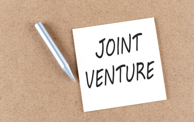 JOINT VENTURE text on sticky note on cork board with pencil