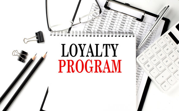 LOYALTY PROGRAM word on notepad with clipboard , chart and calculator, business concept