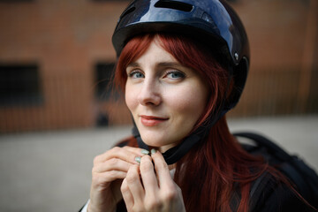 Portrait of businesswoman commuter on the way to work putting on cycling helmet, sustainable...