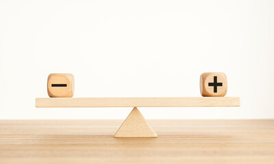 Plus and minus balance concept. Positive and negative symbols on wooden blocks are in balance on a...