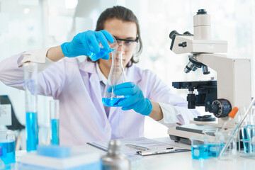 Fototapeta premium Laboratory research concept, Scientist pour solution into beaker for research of vaccine and drug