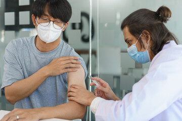 Vaccination concept, Male doctor in face mask injecting vaccine against covid-19 for male patient - obrazy, fototapety, plakaty