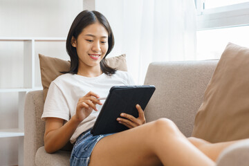Cozy lifestyle concept, Young woman lying on couch and using tablet to surf social media at home