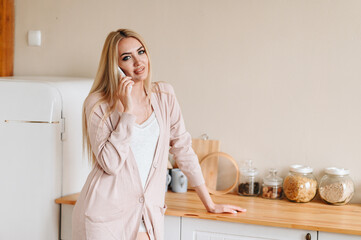 The wife is talking on the phone in the kitchen. Lifestyle everyday routine of a woman