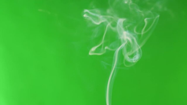 Smoke jet on green chroma key background. Smoking, steam clouds of vapour close-up. Burning, fog. 