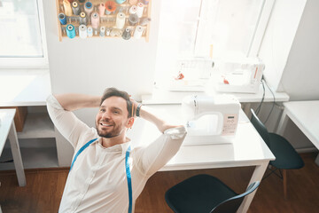 Happy young fashion designer having rest in atelier