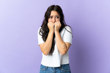 Young caucasian woman isolated on purple background nervous and scared putting hands to mouth