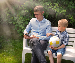 Naklejka premium The boy calls his father for a walk. But father is busy on the phone