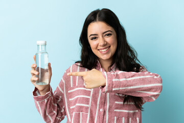 Young woman with a water isolated on blue background and pointing it