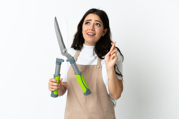 Young caucasian woman holding a plant isolated on white background with fingers crossing and wishing the best