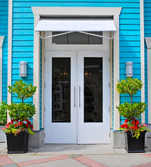A shop entrance with decorative flowers at the doors