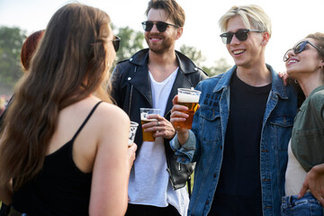 Group of young caucasian friends drinking beer and  having fun on music festival