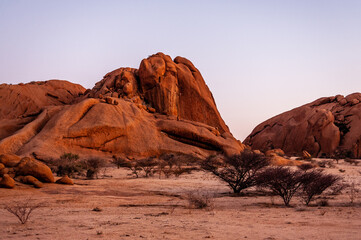 Fototapeta na wymiar Bold rock formations glowing bright orange in the last rays of the setting sun. Spitzkoppe, Namibia.