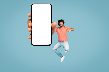 Happy hindu guy jumping up with smartphone, mockup