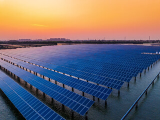 Fototapeta premium Aerial view of solar power station at beautiful sunset. solar photovoltaic power station on water. green energy concept.