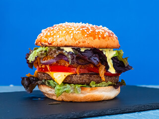 Vegan burger consisting on a slate plate. blue background. Horizontal
