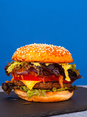 Vegan burger on a slate plate. blue background. Vertical.
