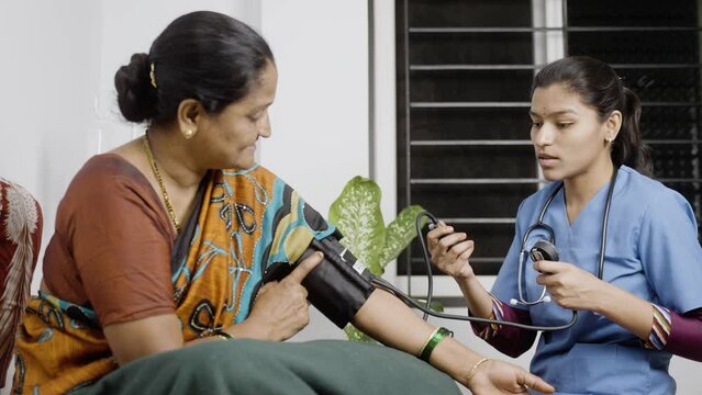 Nurse at home checking BP or blood pressure of sick woman patient at nursing home - cocept of consultation, home checkup and medicare treatment