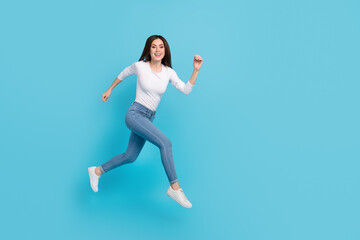 Fototapeta na wymiar Photo of dreamy excited woman wear white shirt jumping high running fast empty space isolated blue color background