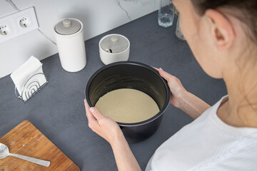 Young woman holding a baking dish with dough. Top view, flat lay