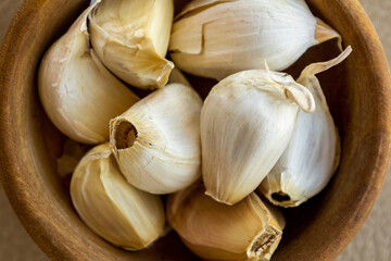 Close up of garlic cloves in small wooden bowl