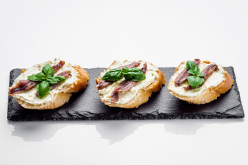 sandwich with anchovy fillets on a serving tray on a white background