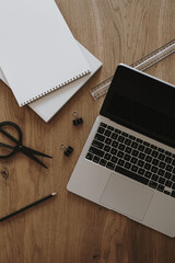 Laptop, notebook, stationery on brown wooden table. Flat lay, top view aesthetic home office workspace