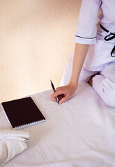 Young caucasian woman from the massage and epilation procedure, uses a smartphone to record clients in a beauty salon, sits on a sofa in the office and writes on paper