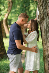 Fototapeta premium Portrait of lovely happy couple looking to each other at summer park, man embracing woman