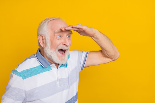 Portrait of attractive cheerful amazed grey haired man searching copy space isolated over shine yellow color background
