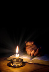 Hands folded in prayer over Scriptures