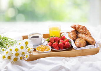 Breakfast in bed. Tray with cup of coffee , orange juice, fresh fruits and bunch of daisy flowers