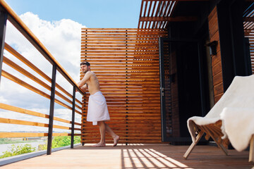 Fototapeta premium Side view of handsome man relaxing on terrace at spa complex