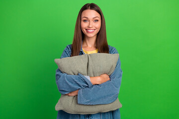 Fototapeta premium Photo of adorable lovely satisfied girl hands hold pillow toothy beaming smile isolated on green color background