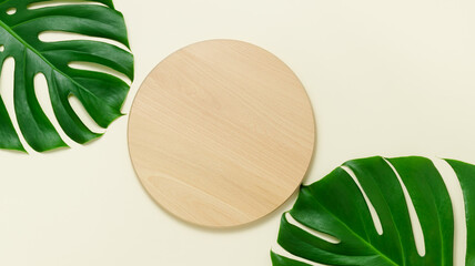 Wooden desk product podium with green monstera leaves top view, display for summer product...