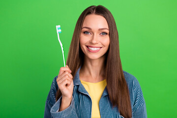 Portrait of cheerful charming lady hand hold toothbrush beaming smile isolated on green color...