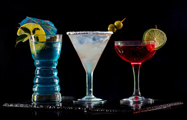 Cocktails set, collection on bar counter in a restaurant, pub. Fresh drink with vodka, lemonade, blue liquor. Alcoholic cooler beverage on an isolated black background