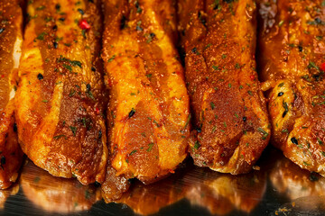 Raw uncooked pork belly marinated in Asian style with herbs and spices on a metal tray. Meat industry and product known for tenderness and great flavor. Summer range meat. Close up