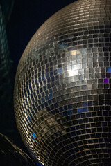 Disco ball in a dark room. Party and having fun concept in a club. Popular disco style item. Sphere with mirrors for creating lighting effects with reflection of color light.
