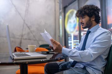 Man sitting sideways to camera studying papers