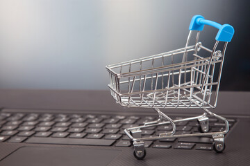 Model of a grocery cart on the background of a laptop. online shopping websites