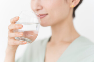 透明なグラスに入ったおいしい水を飲んでいる女性