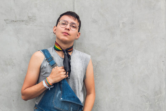teen gay boy with glasses looking at camera on gray city wall