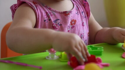 Sculpture and clay modeling for children. Girl 2-5 years old forming and shaping pink play dough by fingers and plastic modeling knife. Enhancing fine motor skills and kid creativity using play clay